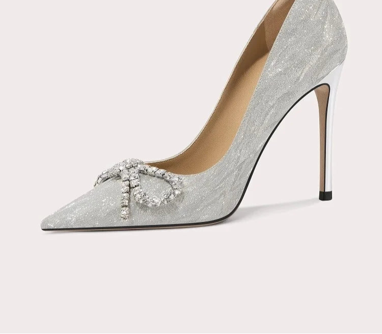 Silver high-heeled shoe with decorative element on a light gray background