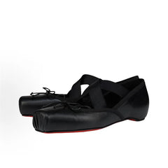 Black ballet shoes with red soles on a white background