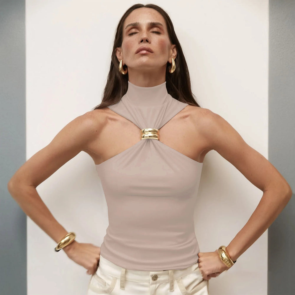 Woman wearing a beige halter top with a gold accent against a neutral background