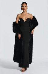 Woman wearing a black strapless gown with a fur stole on a white background