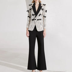 Person wearing a stylish black and white outfit with a sequined jacket on a light gray background