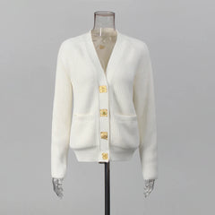 White cardigan with gold buttons on a mannequin against a gray background