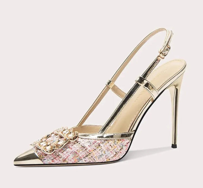 Gold high-heeled shoe with decorative elements on a white background