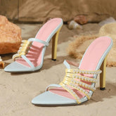 Beaded strappy pointed toe heeled mules on sand.