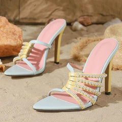 Beaded strappy pointed toe heeled mules on sand.