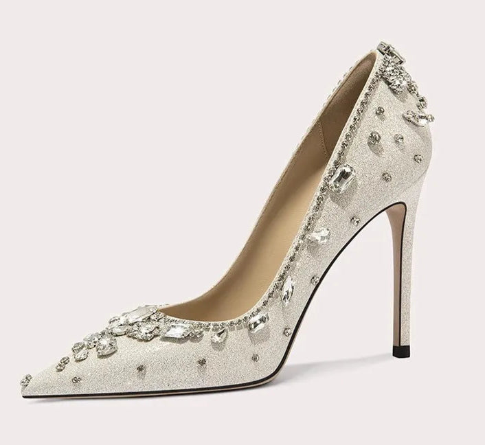 Silver high-heeled shoe with embellishments on a light gray background