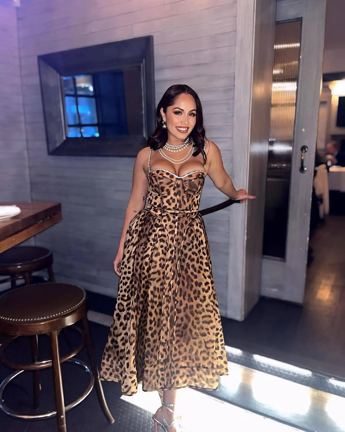 Woman in a leopard print dress standing in a restaurant setting