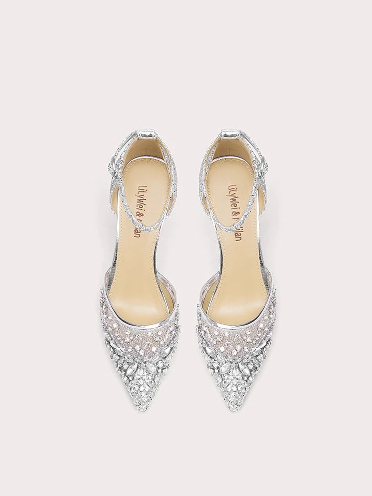 Pair of silver pointed-toe high heels with embellishments on a light pink background