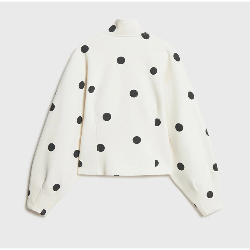 White long-sleeve top with black polka dots on a light gray background