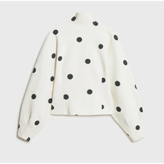 White long-sleeve top with black polka dots on a light gray background
