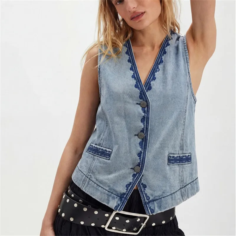 Light wash denim vest with blue embroidered trim and button front closure.