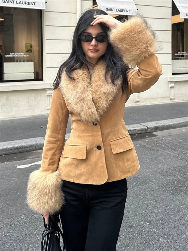 Woman wearing a tan suede jacket with fur trim on a city street.
