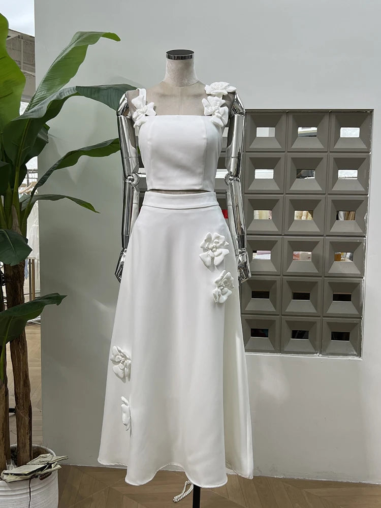 White dress with floral embellishments on a mannequin against a white wall.