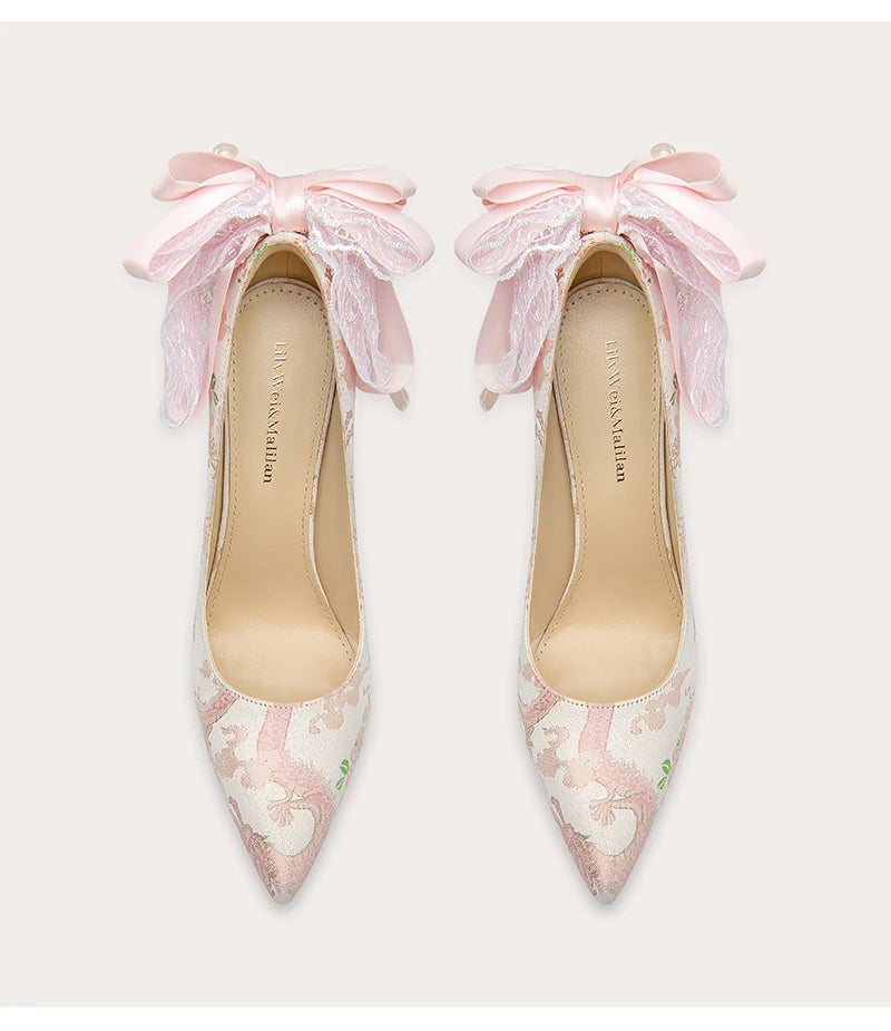 Pair of pink floral high heels with ruffled straps on a white background