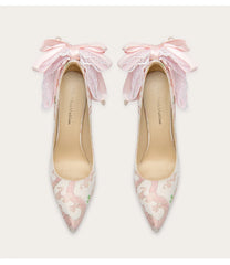 Pair of pink floral high heels with ruffled straps on a white background