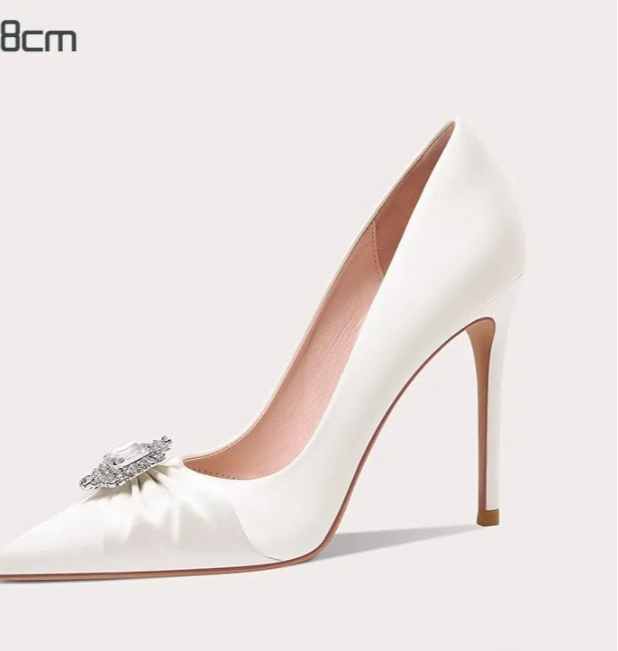 White high-heeled shoe with a decorative bow on a light gray background
