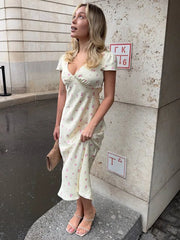 Woman in a white floral dress standing against a wall with a sign.