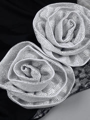 Two silver rose-shaped decorative elements on a black and gray background