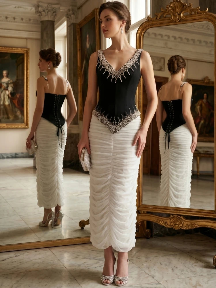 Back view of a woman in a black beaded V-neck sleeveless top with lace-up closure and a white ruched floor-length skirt.