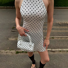 Person wearing a polka dot dress and matching handbag on a pavement.