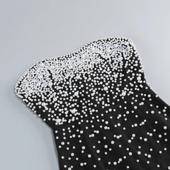 Black dress with white pearl embellishments on a gray background