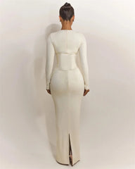 Person wearing a white long-sleeve dress with a slit on a plain background