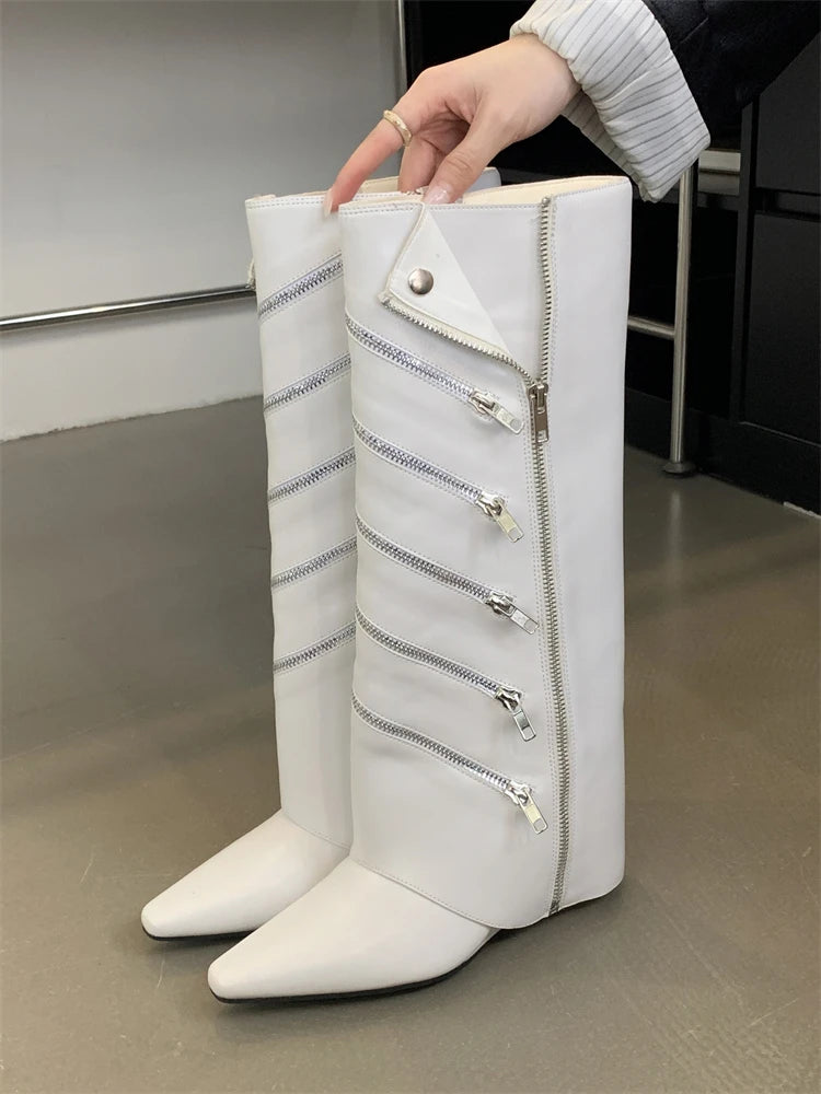 White knee-high boots with zippers held by a hand on a neutral background