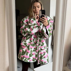 Woman wearing a floral patterned coat taking a mirror selfie.