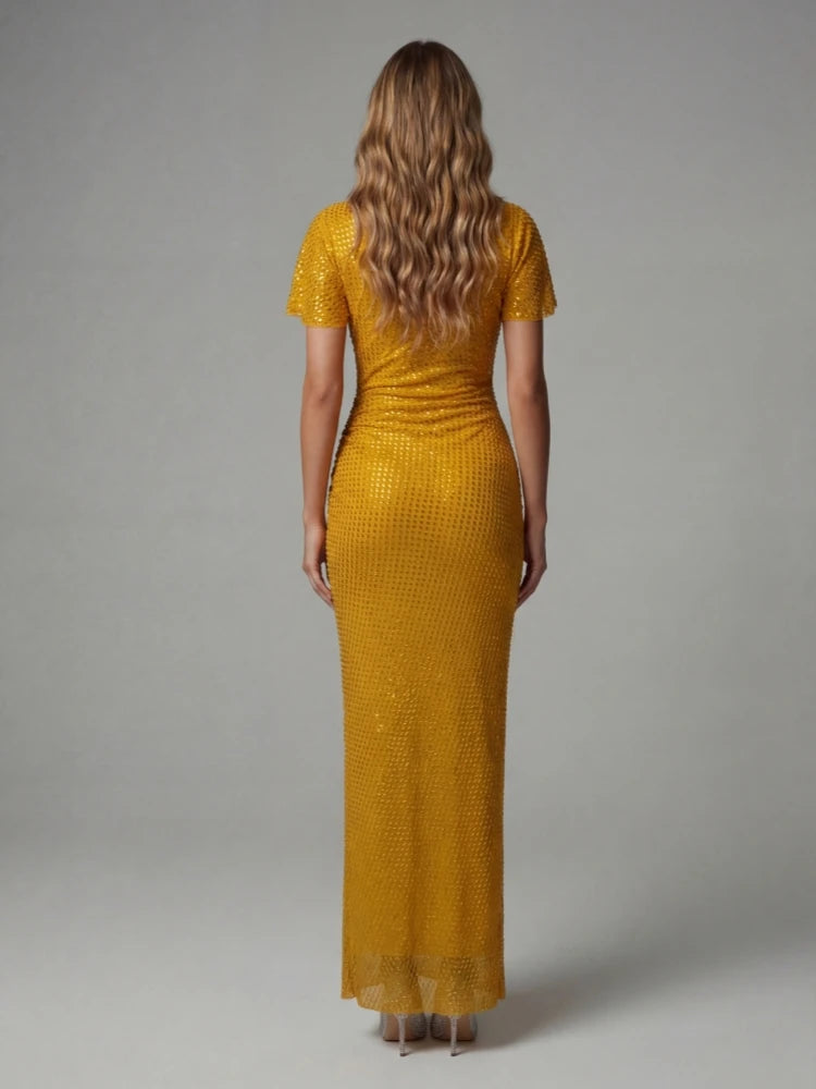 Woman wearing a gold dress with a textured pattern on a grey background