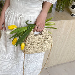 Person holding a straw bag with yellow tulips, wearing a white dress.