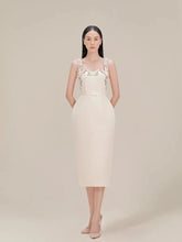 Woman wearing a white dress with floral straps against a beige background