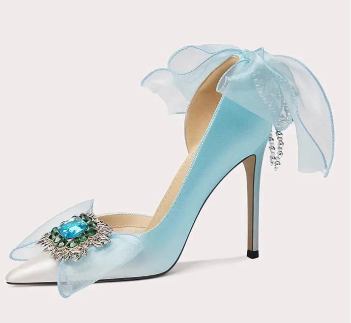 Light blue high-heeled shoe with decorative bow and gemstone on a white background
