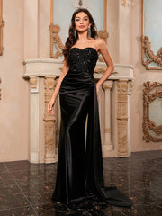 Woman in a black evening gown standing in an ornate room.