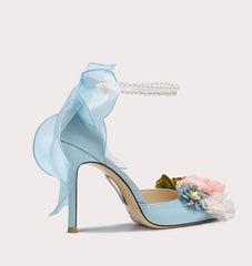 Light blue high-heeled shoes with floral decorations on a light gray background