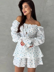 Woman wearing a white floral off-shoulder dress against a gray background