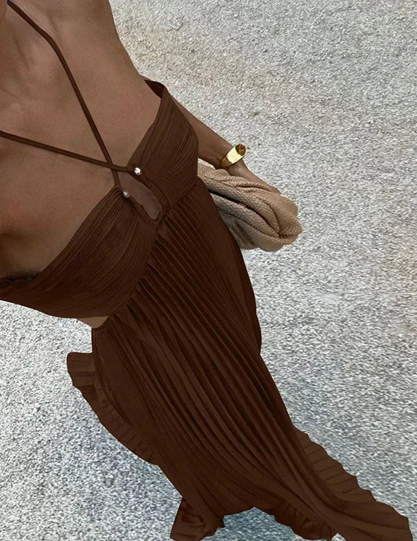 Brown pleated dress with thin straps on a textured surface