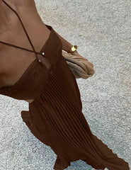 Brown pleated dress with thin straps on a textured surface