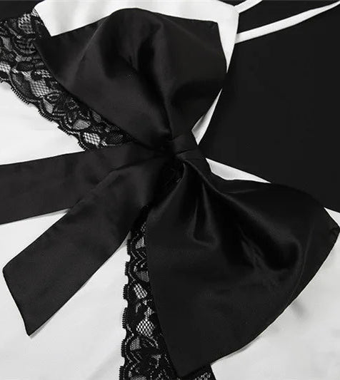 Close-up of a black bow and lace detail on a white garment.