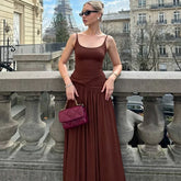Woman in a brown dress with a red handbag standing in front of the Eiffel Tower.