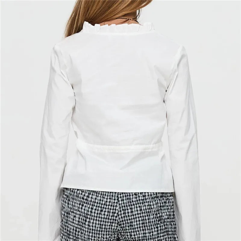 Person wearing a white long-sleeve shirt with a plain background