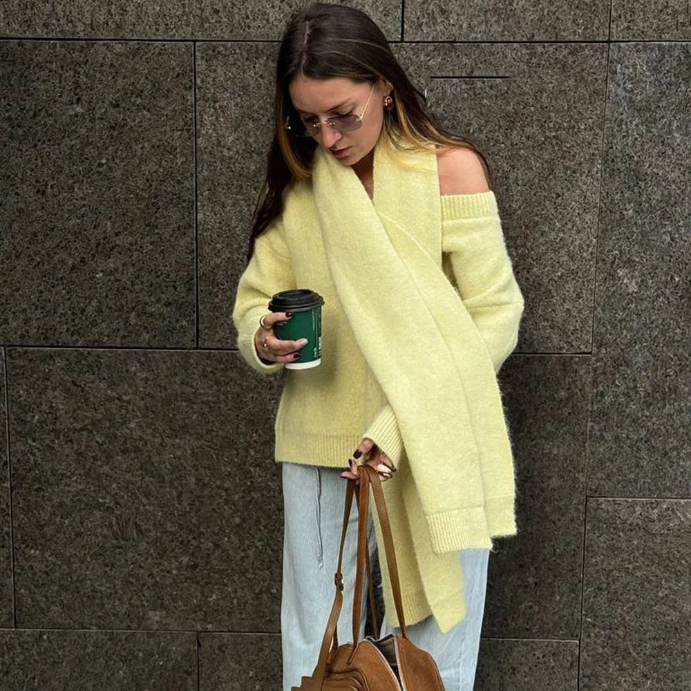 Woman in a yellow sweater holding a coffee cup against a gray wall
