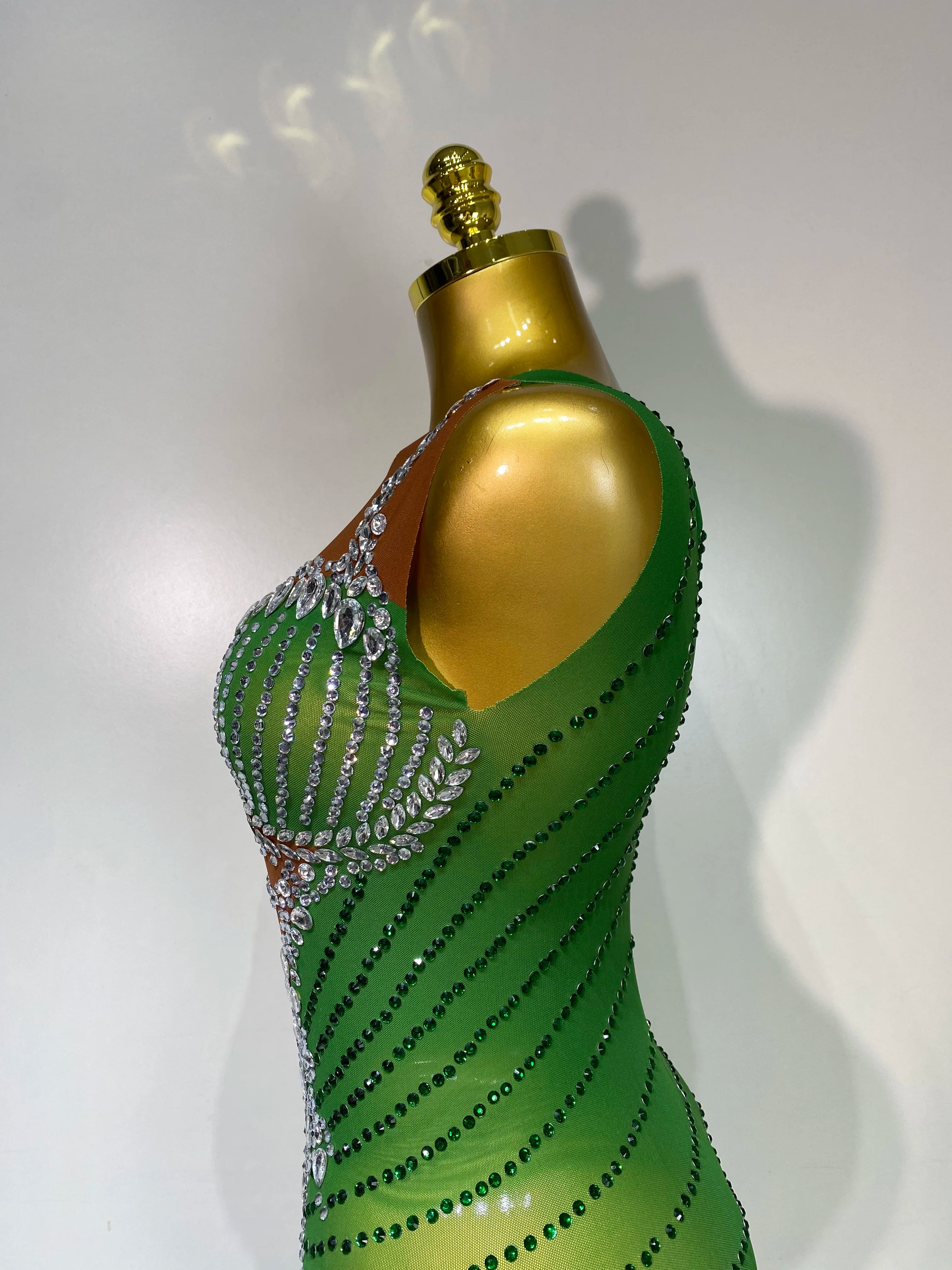 Green evening gown with embellishments on a mannequin against a white background