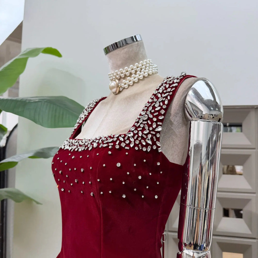 Red dress with pearl embellishments on a mannequin against a neutral background