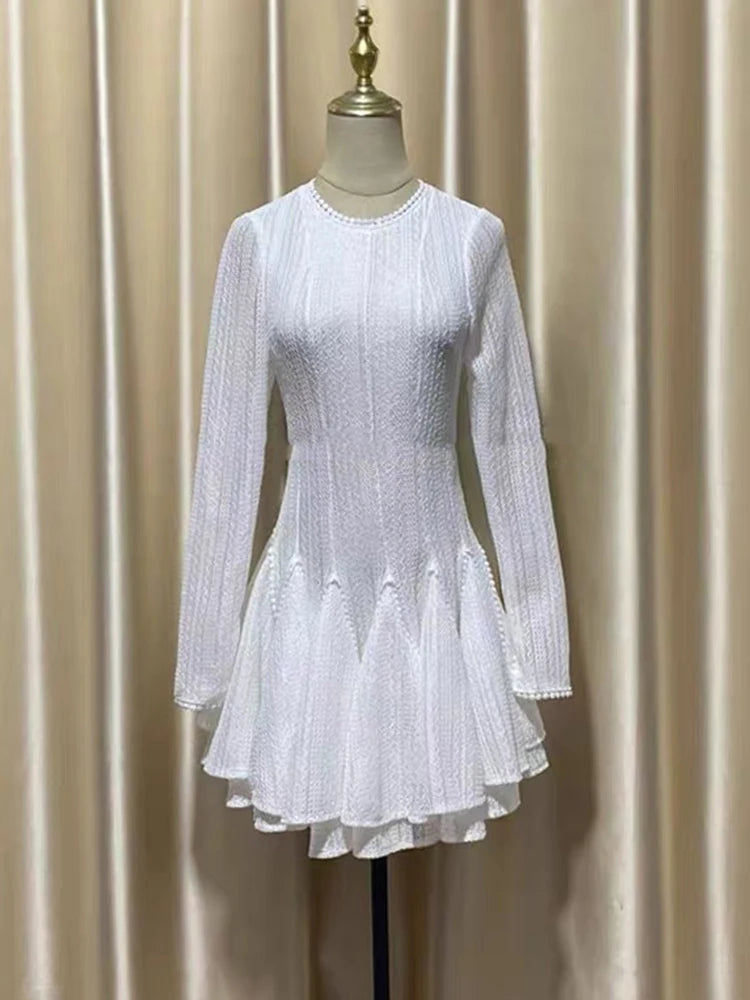 White dress on a mannequin against a beige curtain background