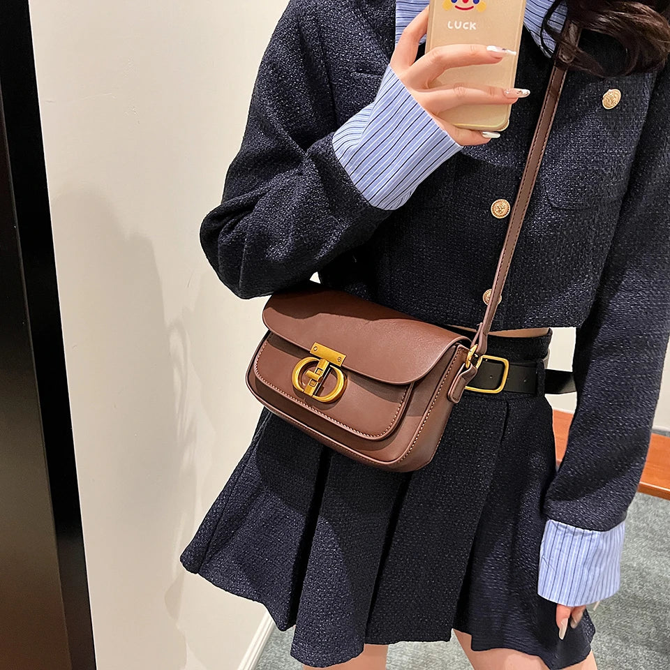 Person wearing a dark outfit with a brown leather bag