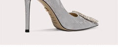 Gray high-heeled shoe with embellishments on a light gray background