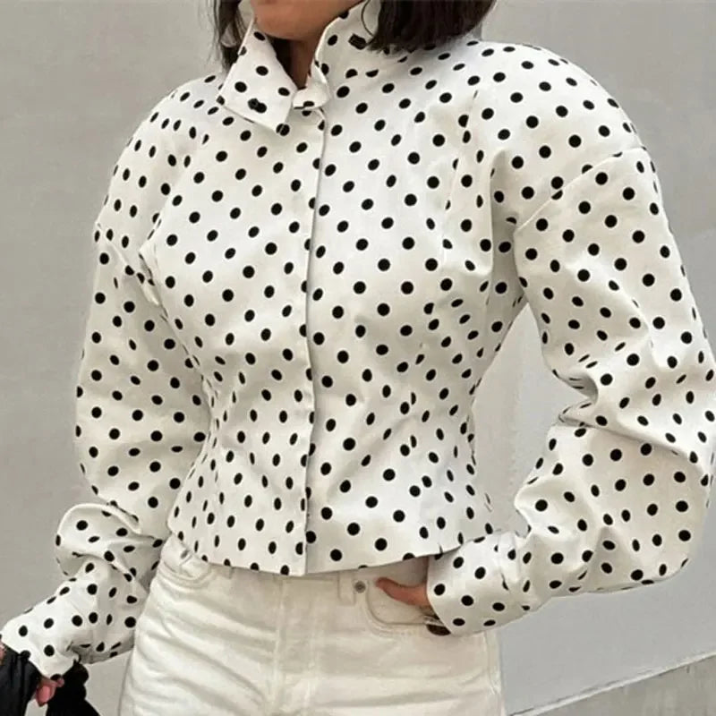 White blouse with black polka dots worn by a person against a neutral background