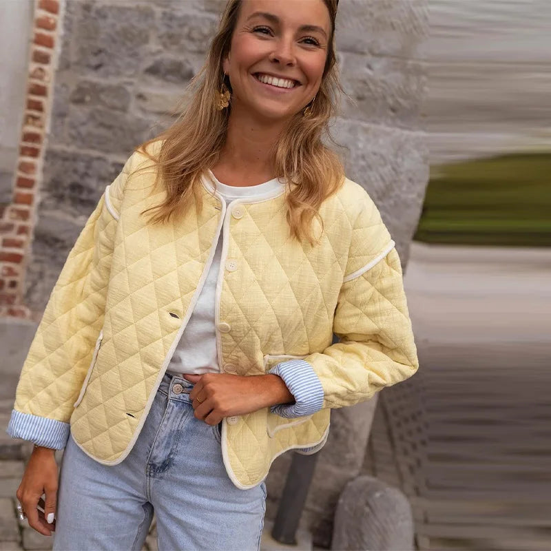 Woman wearing a light yellow quilted jacket with a blurred background