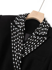 Black coat with a decorative white scarf on a wooden hanger against a white background