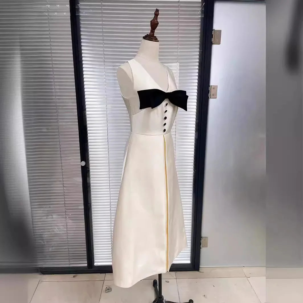 White dress with black bow on a mannequin against a glass door background
